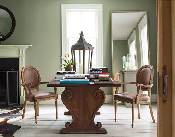 Una sala de estar pintada de verde con mesa de madera adornada y detalles vintage.