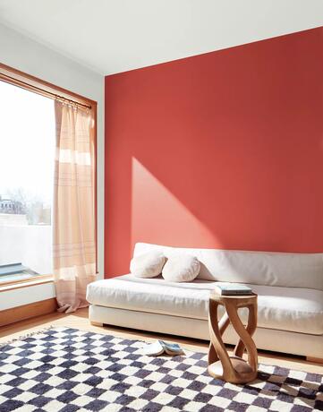 Pared decorativa pintada con Raspberry blush en la sala de estar con sofá blanco