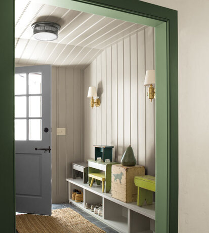 A white painted mudroom, with forest green trim and built in cubbies.