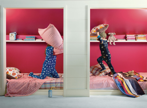 La pintura de color rojo brillante enmarca a dos niños teniendo una pelea de almohadas en un rincón
