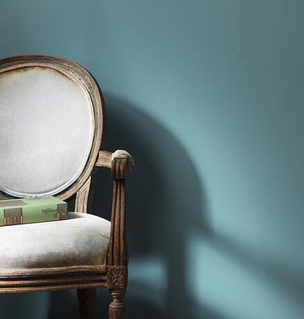 A pale blue-painted wall with a traditional round back chair.