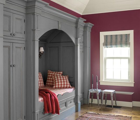 A crisp magenta room with a gray paneled & trim built in bed with red gingham bedding.
