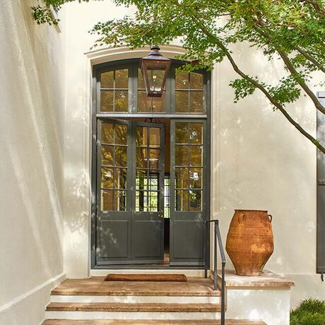 Una casa de estuco pintada de blanco roto con una elegante puerta principal verde oscuro