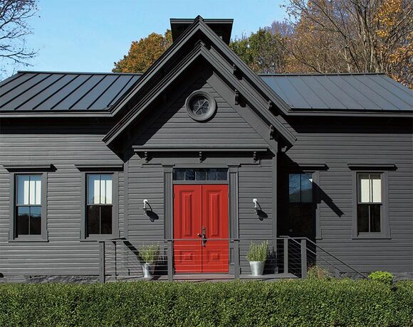 A charcoal gray-painted colonial home that pops with a front door in red.