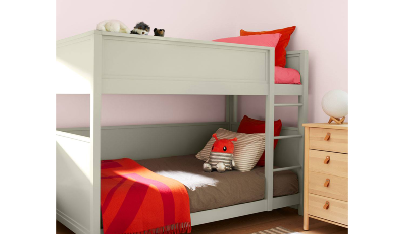 Dormitorio infantil con una litera pintada de verde suave, paredes de color rosa claro