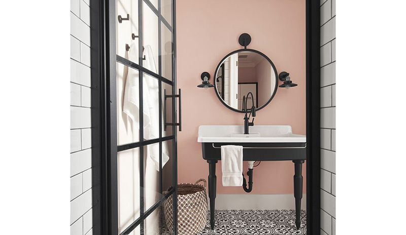 puerta de vidrio con adornos negros que se abre a un refrescante baño pintado de rosa claro